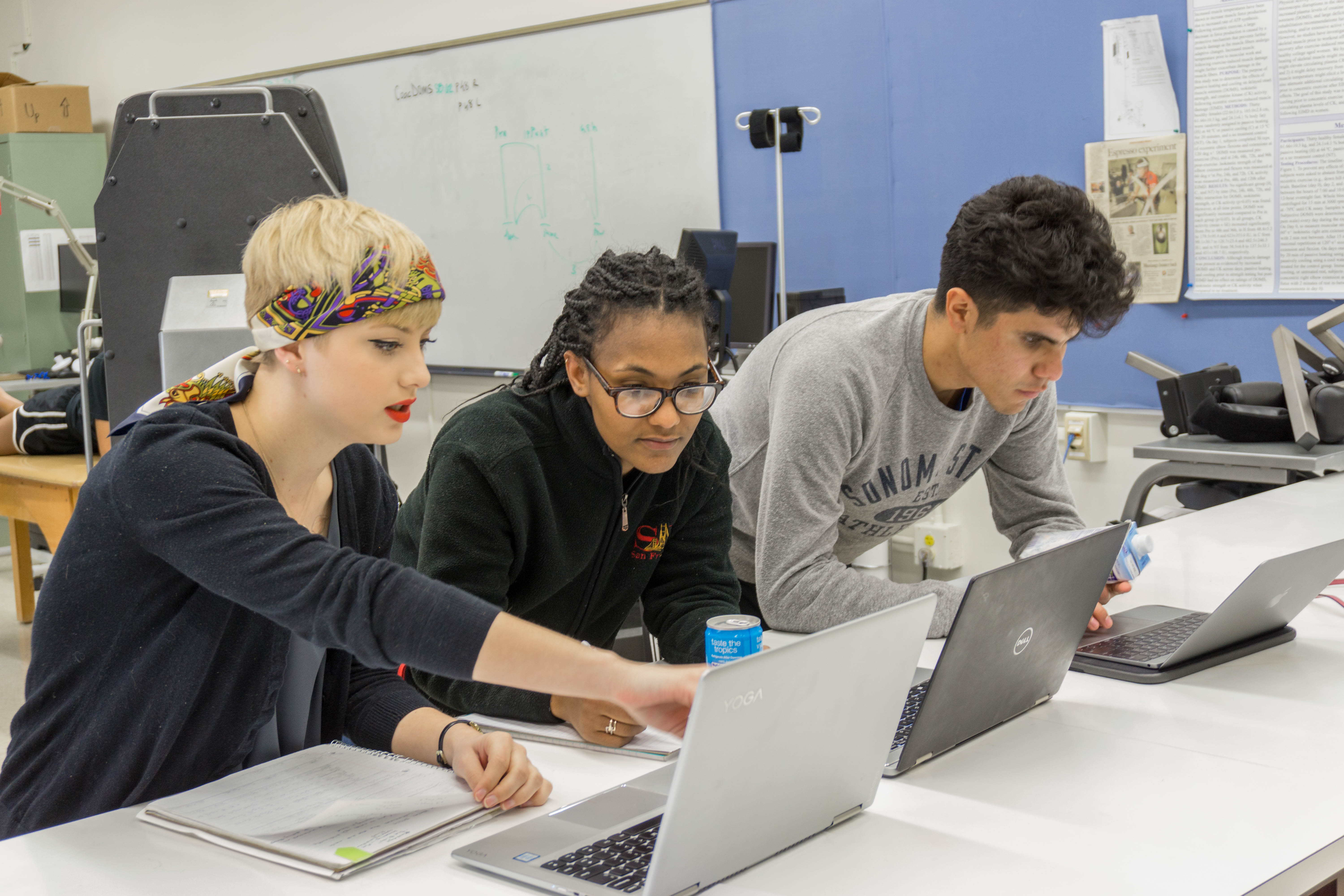 Three Sonoma State students studying on their laptops inside of a classroom lab