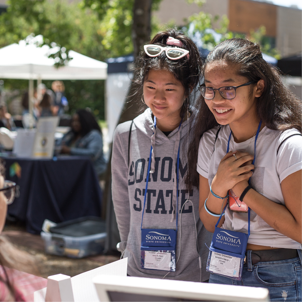 Two students talking to someone tabling