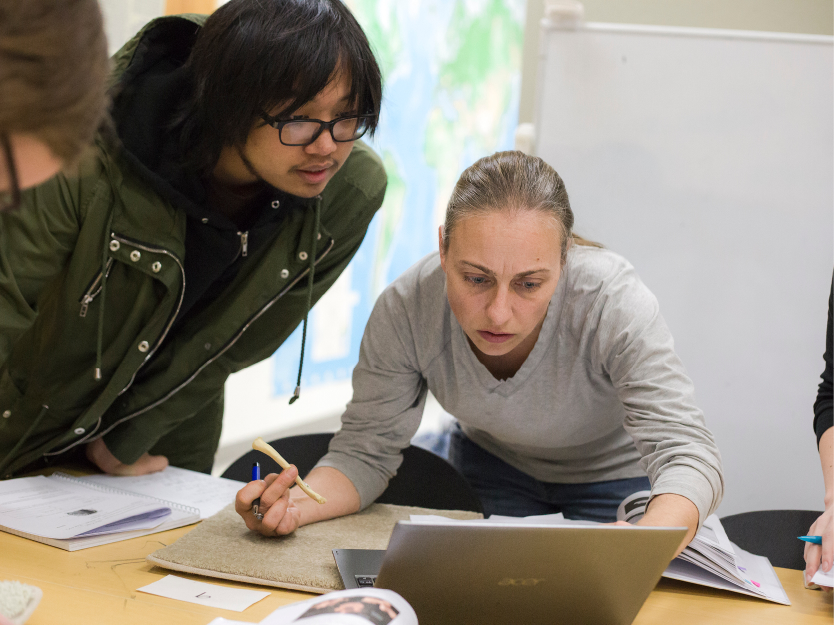 Faculty member meeting with a group of students looking at a piece of paper