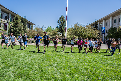 large group of students run in a line across Darwin Quad