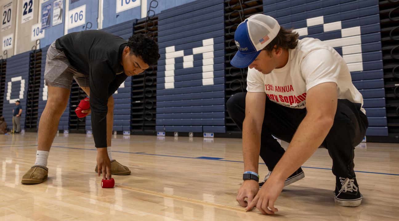 Two students in a kinesiology lab using a tape measure on the floor