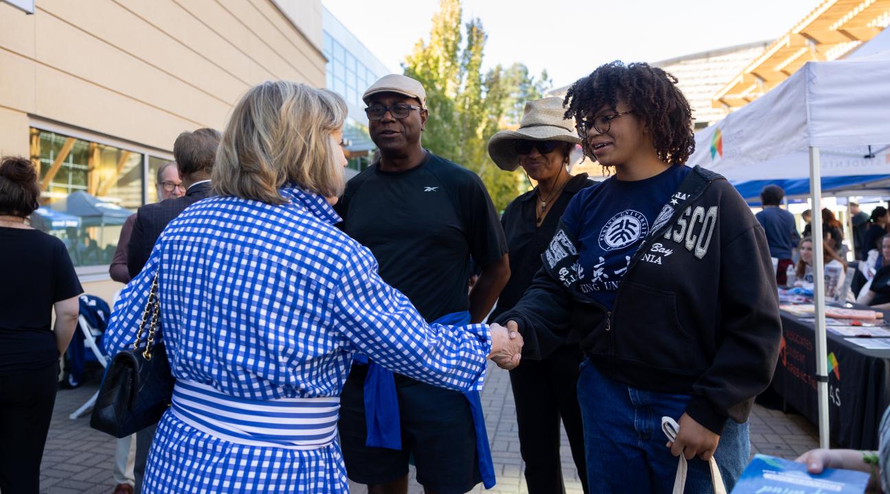 Person shaking a students hand with their parents standing behind them