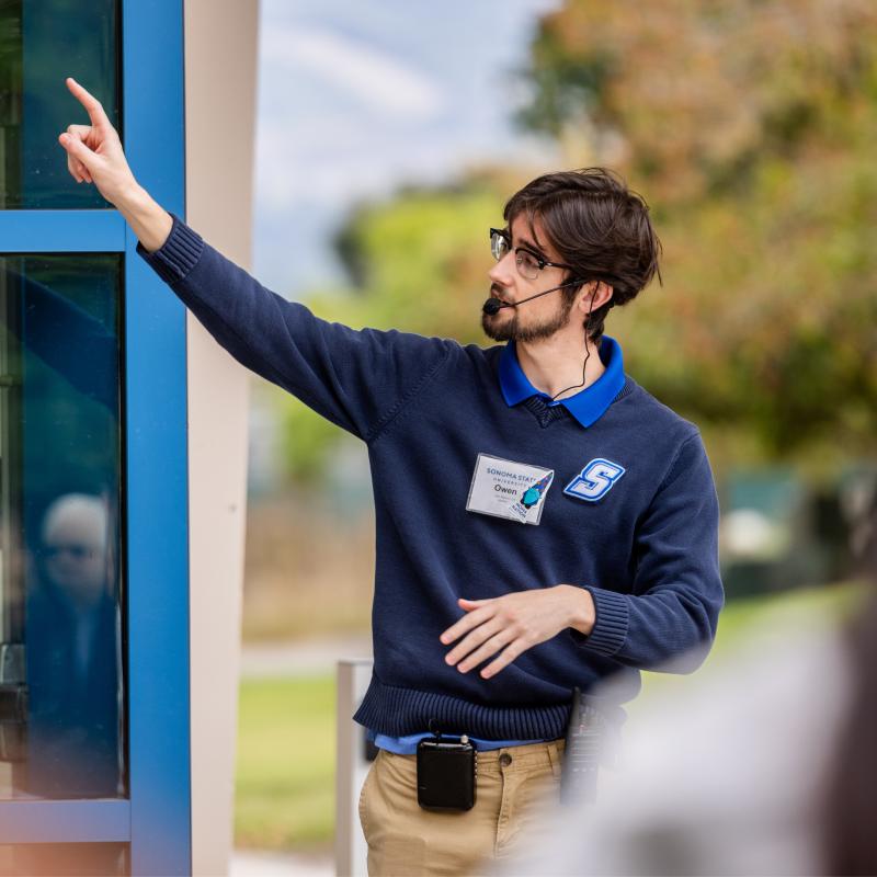Person pointing and wearing a microphone leading a tour group