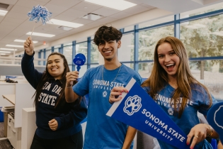 Students smiling and holding a SSU pennant sign