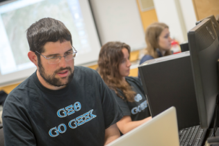 Male student at computer with Geo Go Geek t-shirt