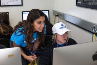 Two students wearing Sonoma State University branded clothing looking at a computer screen