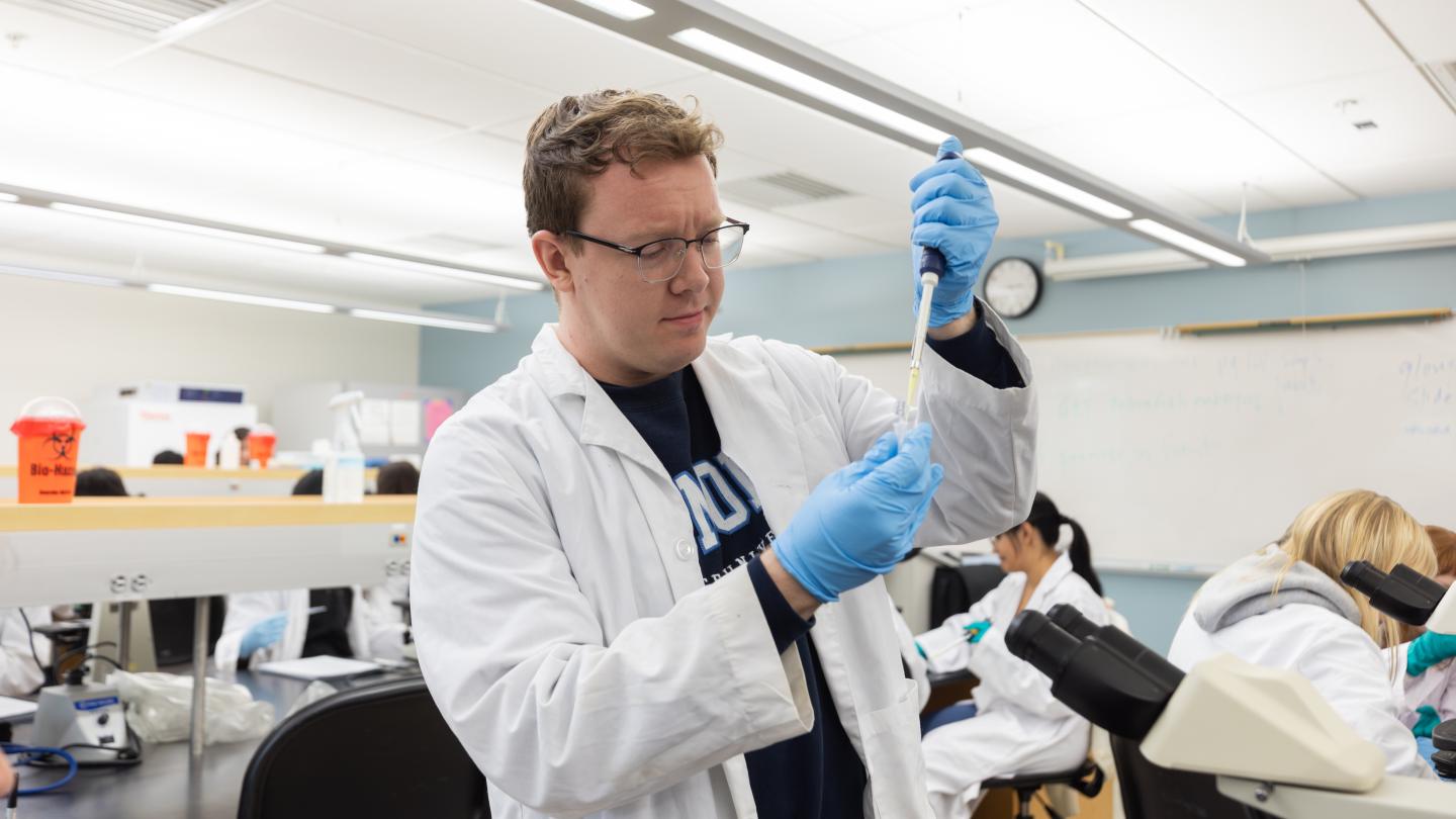 Student in a lab coat with a sample