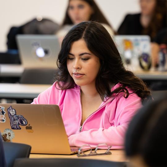 student typing on her computer during class