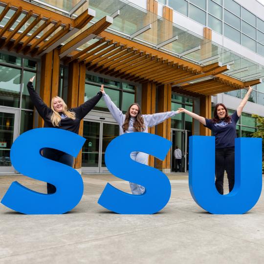3 students taking a photo with the SSU letters