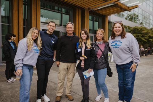 Parent, students and alumni in a group smiling
