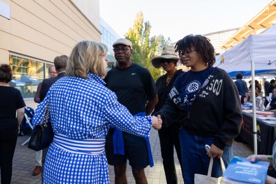 Person shaking a students hand with their parents standing behind them