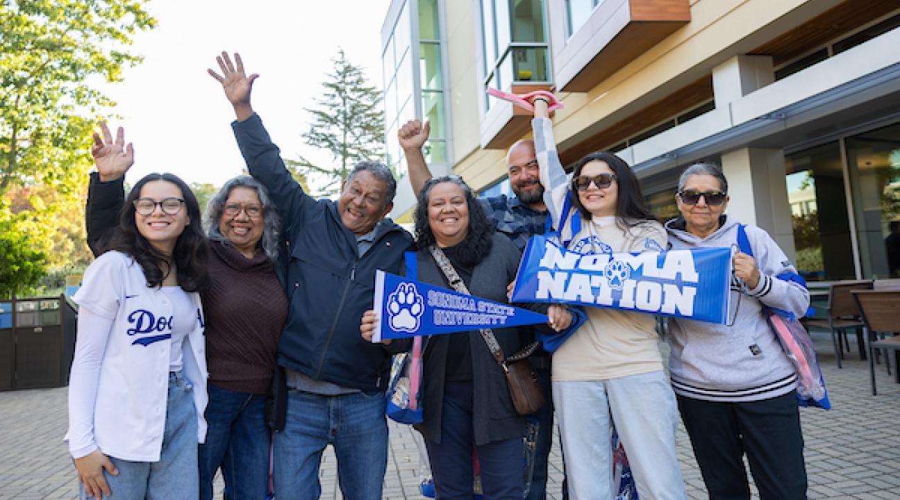 Family holding Noma Nation sign and holding their hands up in the air in celebration