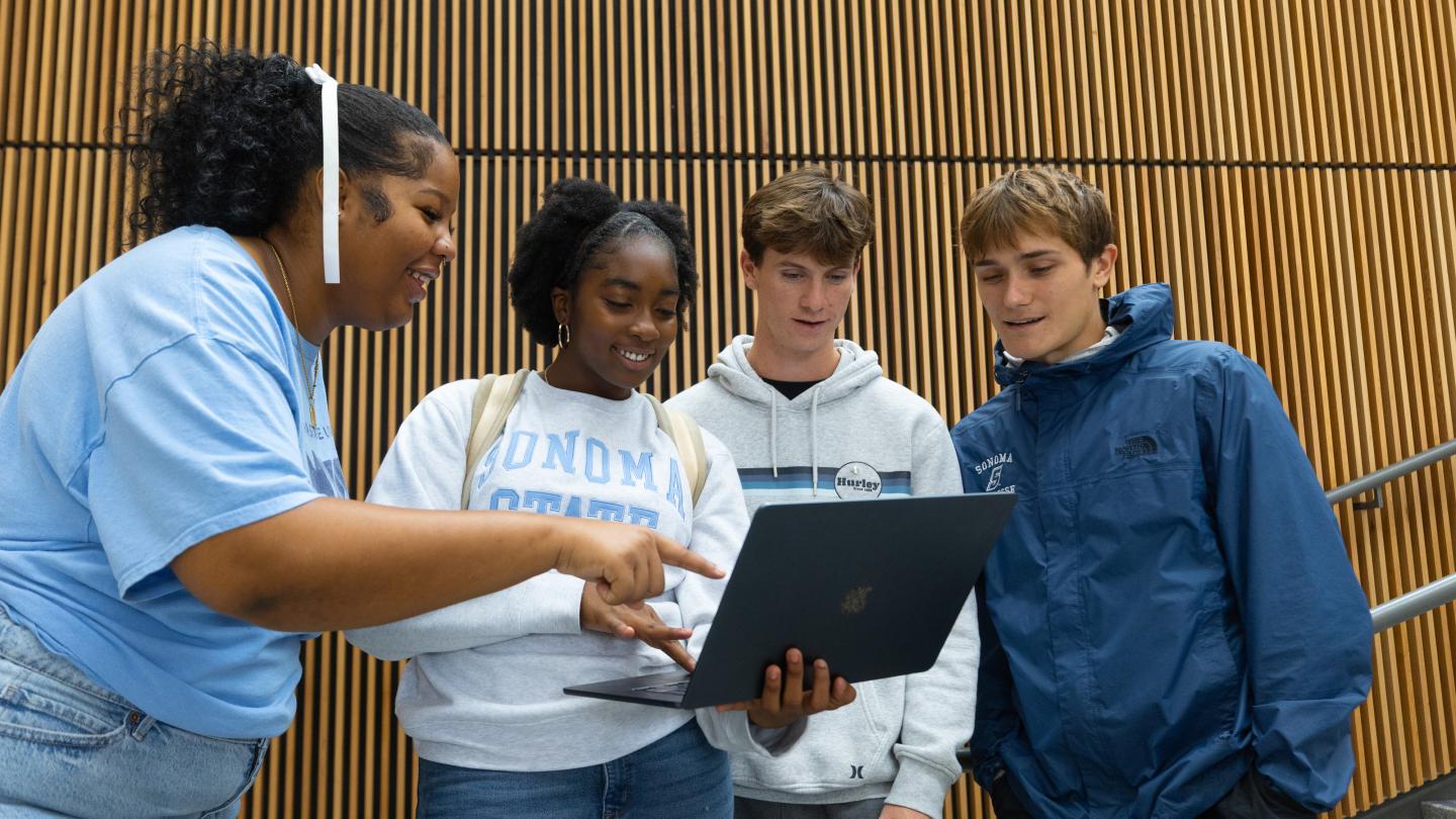 Four students looking at a computer