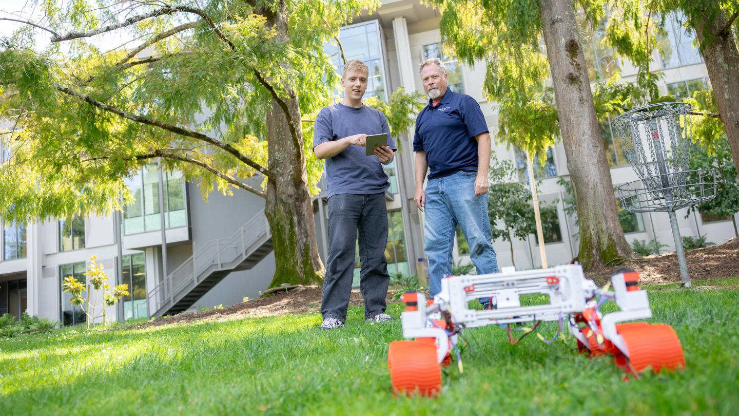 Student and faculty member outside with a robot