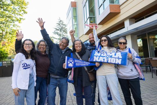 Family holding Noma Nation sign and holding their hands up in the air in celebration
